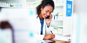 Pharmacy staff member taking written notes while on the phone.