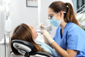 Dental hygienist examines teeth of young woman in a dental chair