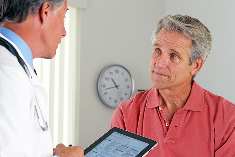 Healthcare team member speaking to senior man during appointment.